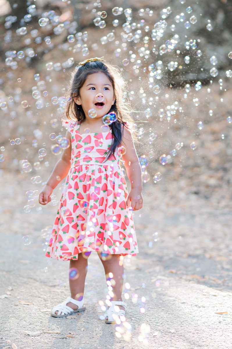 2 year old in flower dress in the middle of bubble at Almaden Park in San Jose, California by photographer Jen Vazquez