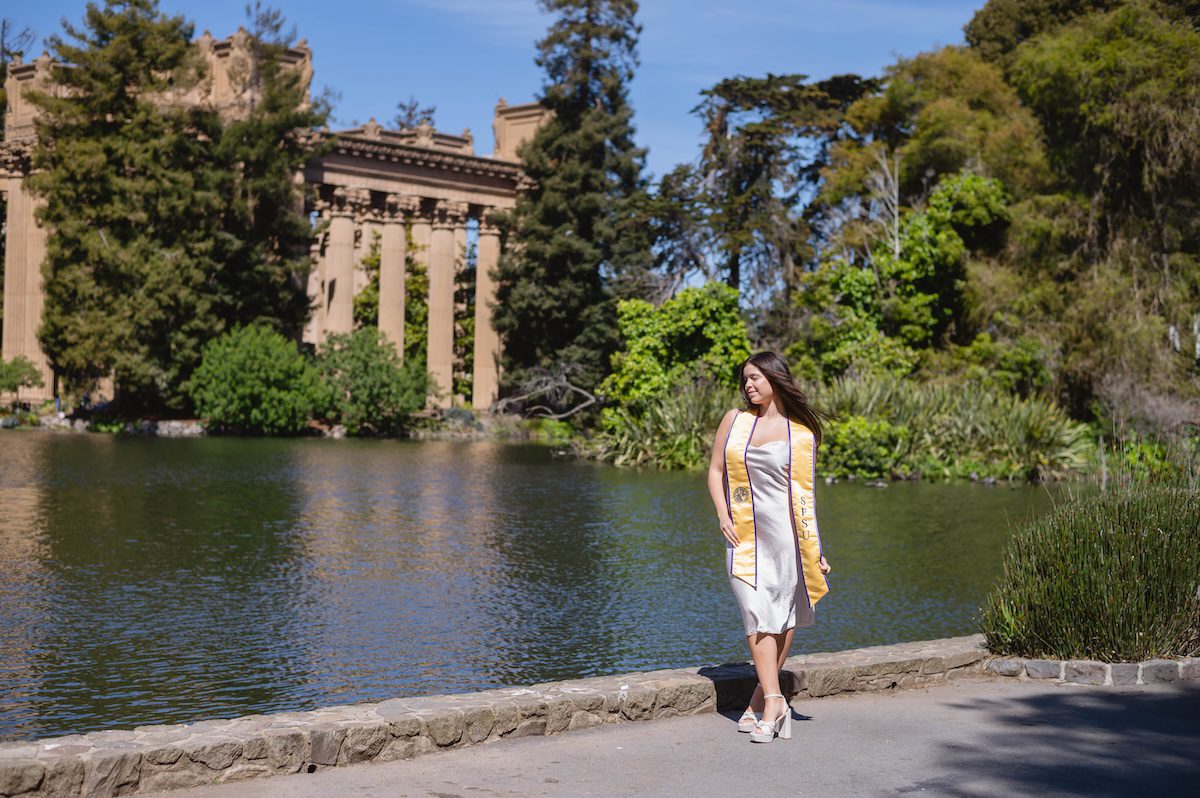 A women in a silk cream dress and graduational stole at