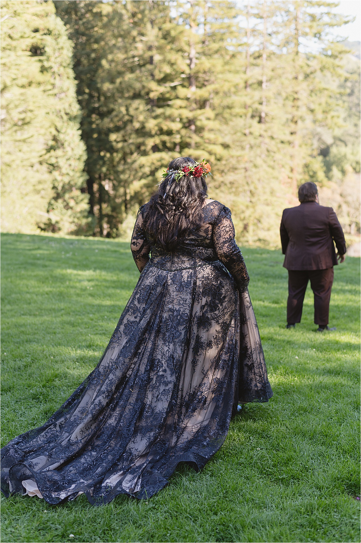 first look with bride wearing a black wedding dress walking toward a groom in a brown suit