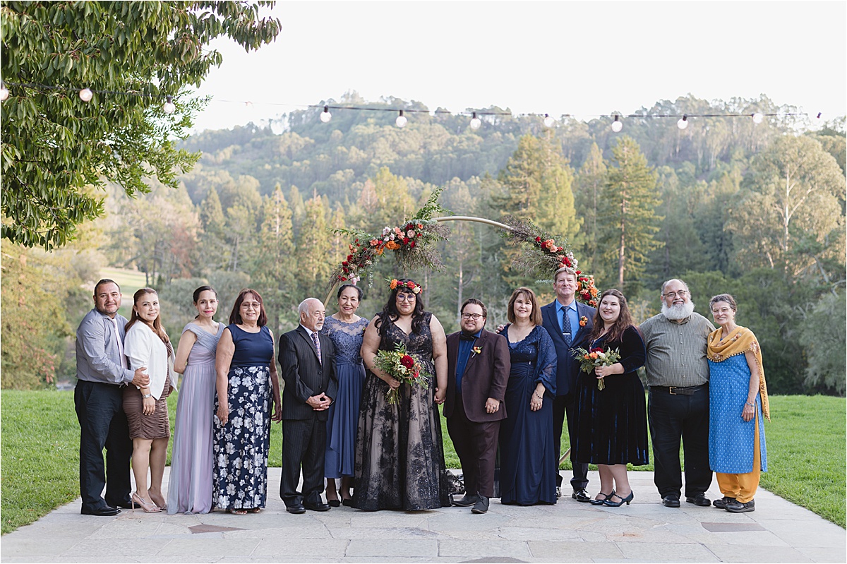 The whole family at a wedding with a bride and groom with the bride wearing a black dress