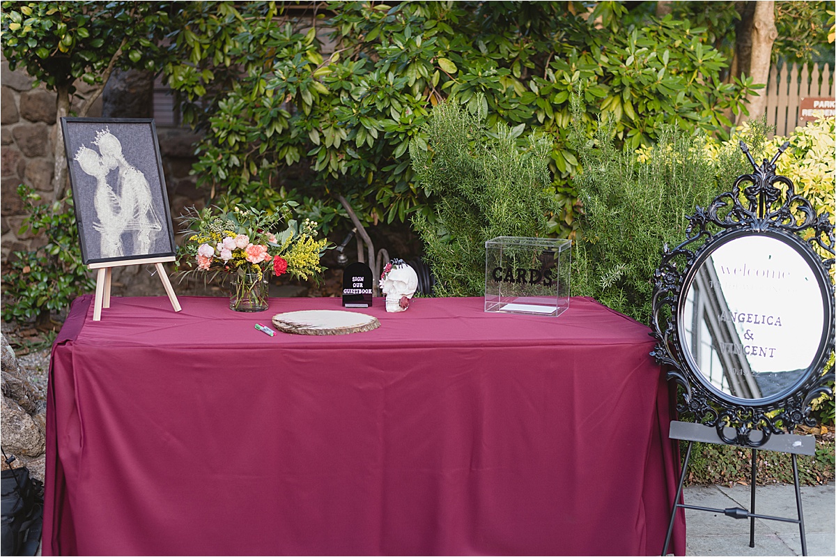 table for a halloween wedding with scull, florals and wooden sign for guests to sign on