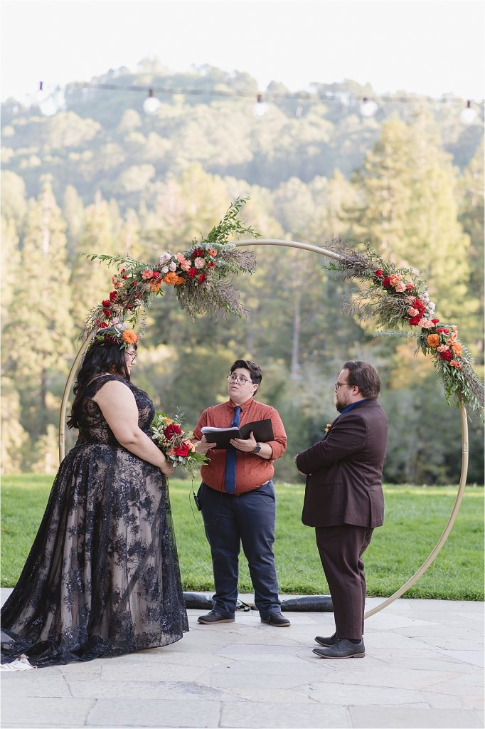 couple at the altar of this halloween wedding with the bride in a black dress