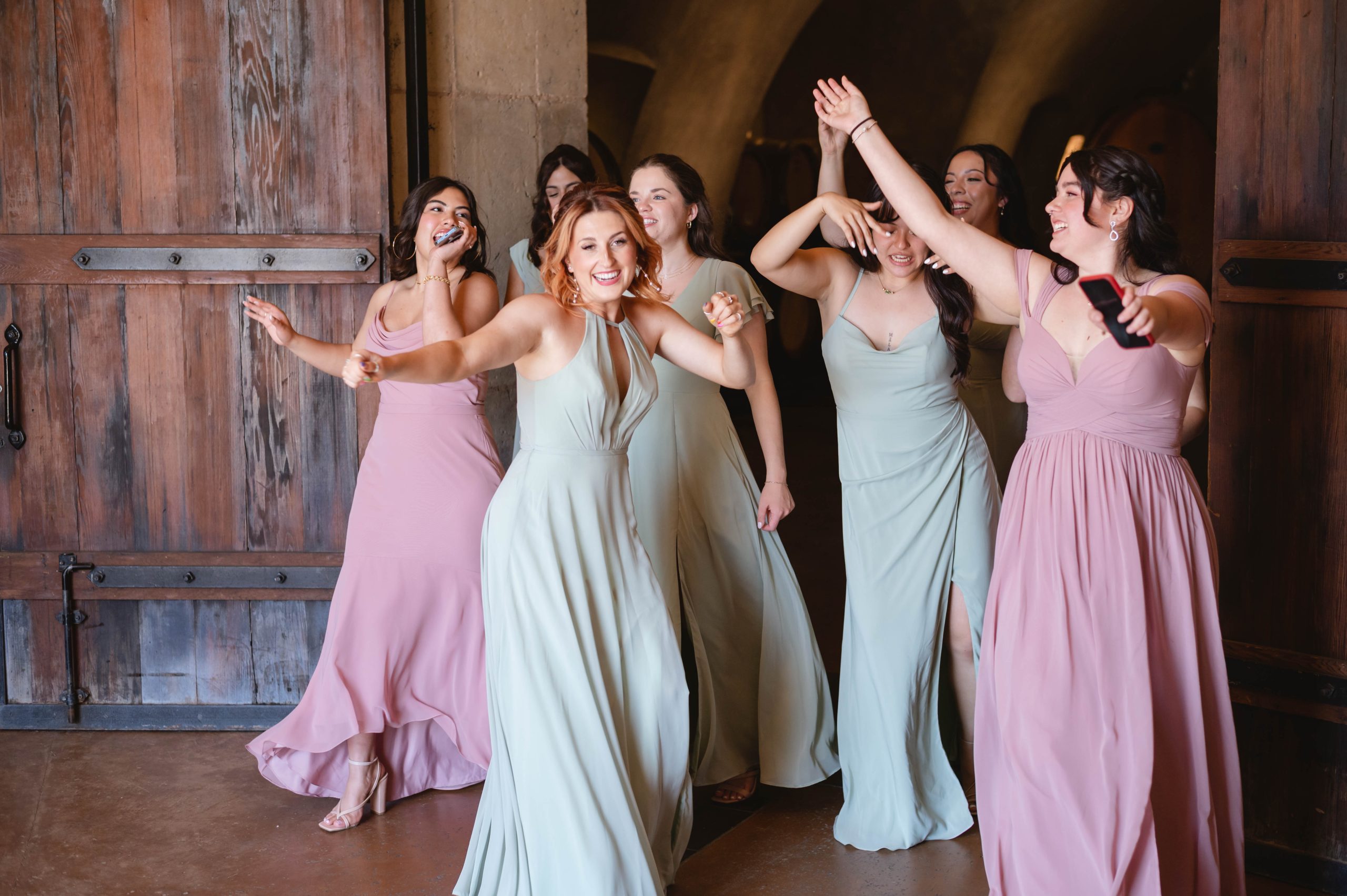 Bridesmaids and Maid of honor MOH dancing with excitement to see the bride reveal her wedding dress to them at Viansa Winery in Sonoma