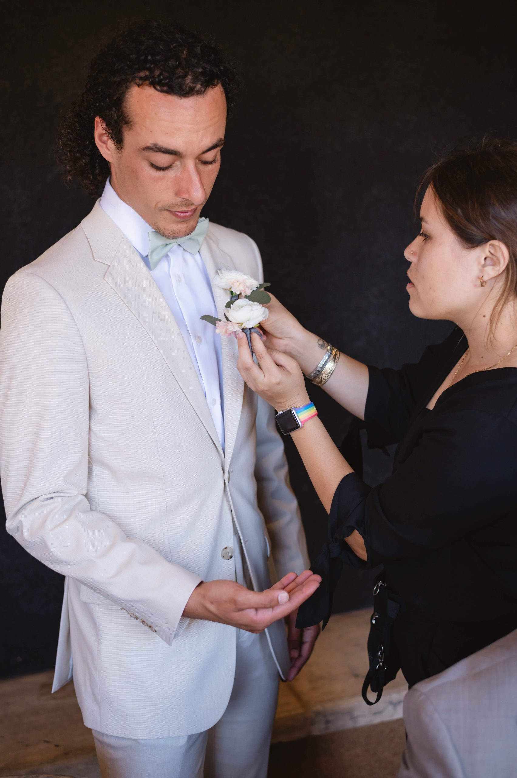 Wedding planner adding boutonniere on groomsmen for wedding at Viansa in Sonoma