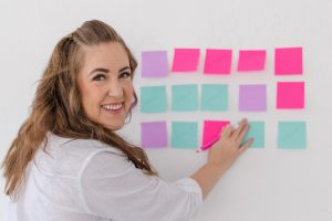 Women smiling at the camera with her hand on sticky notes on the wall in a brand photo in Los Altos California at the Sunlight Space.