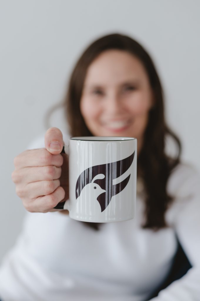 women holding a coffee cup with the Fledgling logo on it. Brand Photo from Jen Vazquez Photography in the Bay Area