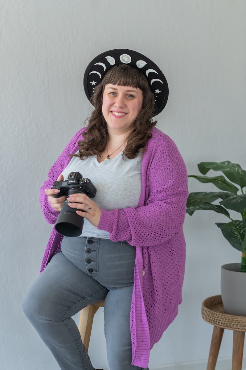 Photographer with her camera in a white shirt with purple sweat and gray jeans with a black hat being photographed by Jen Vazquez Media in the Bay Area of Northern California San Jose