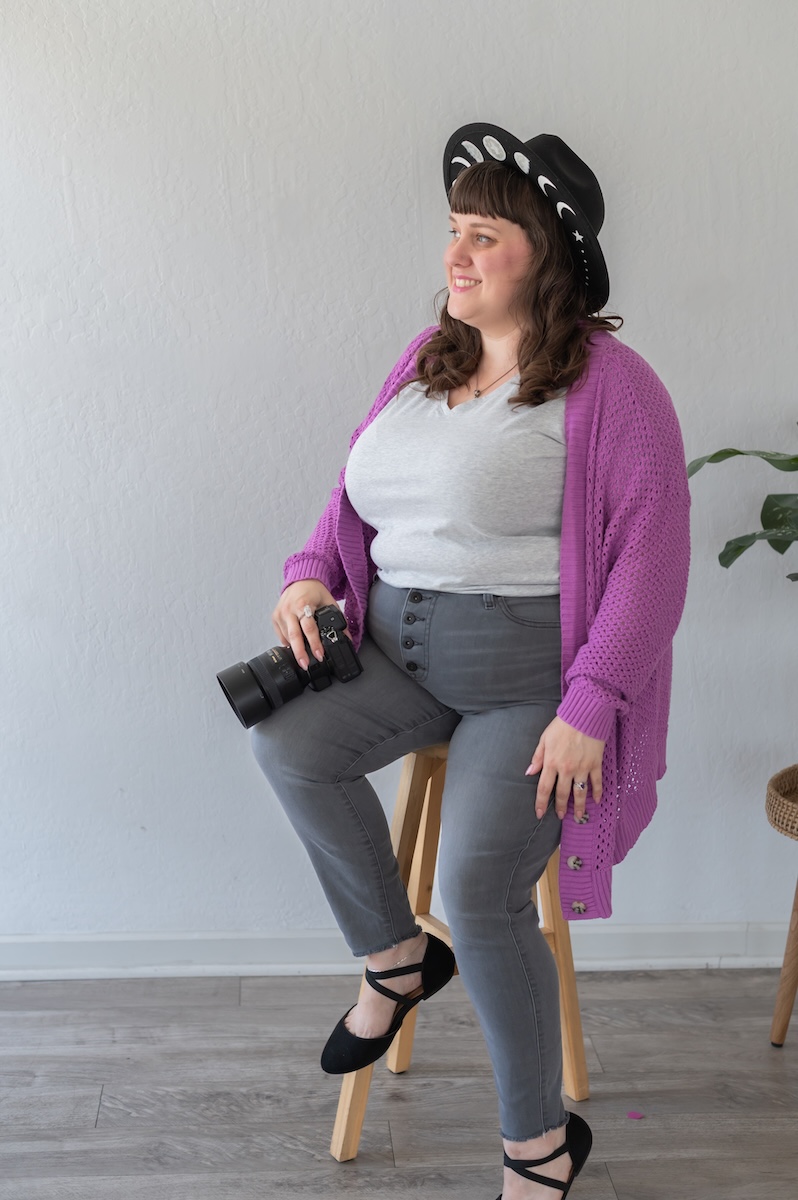 Photographer with her camera in a white shirt with purple sweat and gray jeans with a black hat being photographed by Jen Vazquez Media in the Bay Area of Northern California San Jose
