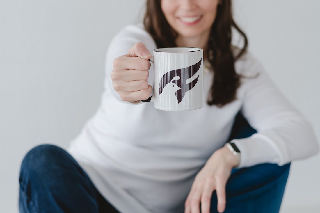a women in white shirt and jeans holding a coffee cup and that's the focus of the image while I talk about how brand photos help you to market your business