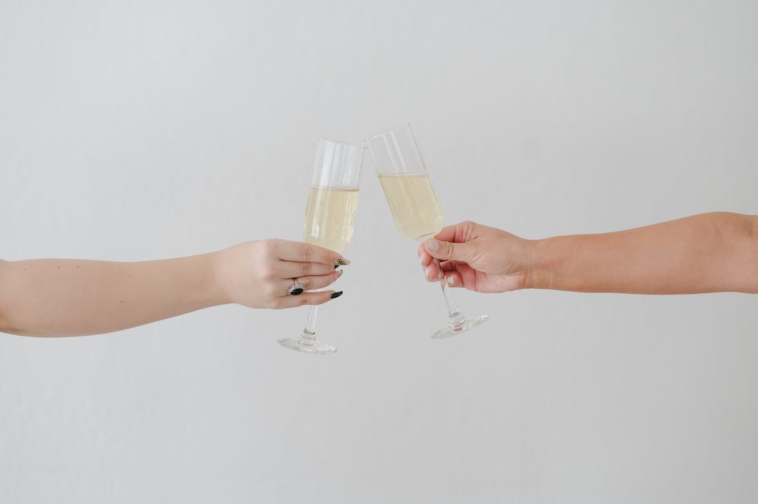 Two champagne classes cheersing while I discuss how brand photos help you to market your business